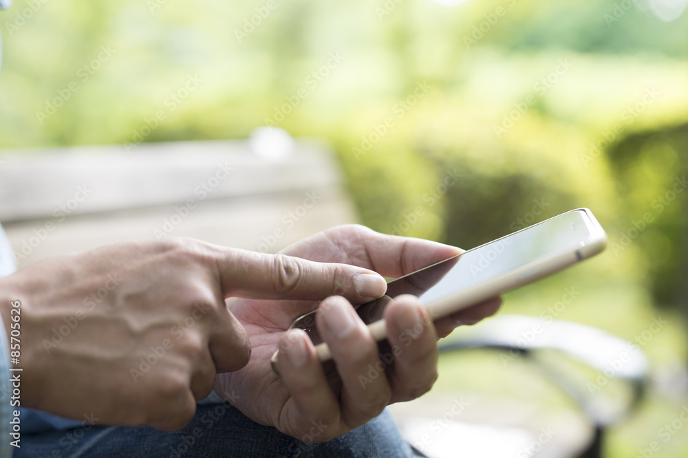 Men are using the smart phone on a bench in the park