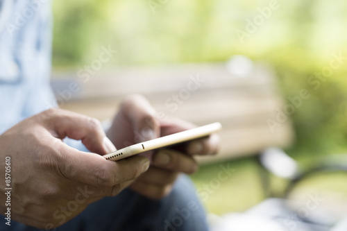 Men are sending an e-mail on a bench in the park