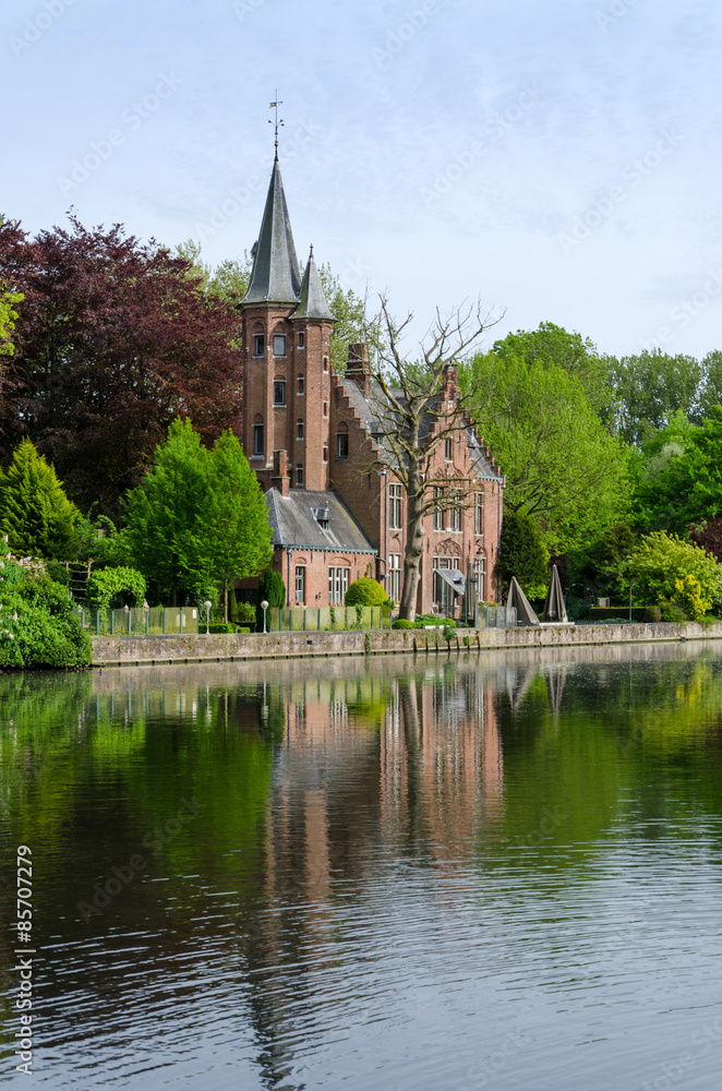 Flemish style castle reflecting in Minnewater lake in Bruges