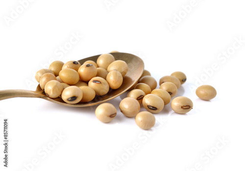 dry soy bean in brass spoon on white background