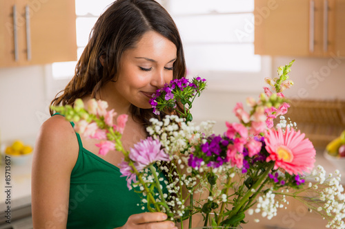 Beautiful woman smelling flowers from her lover at home on valentines day