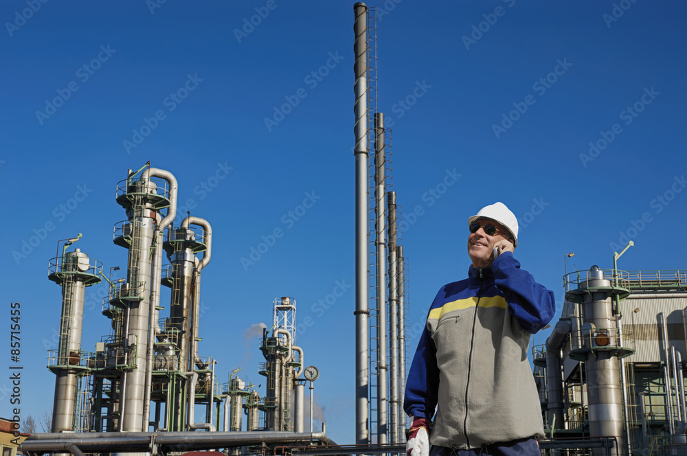 oil worker with large refinery industry in background