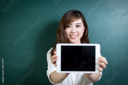 asian beautiful woman holding tablet in front of blackboard