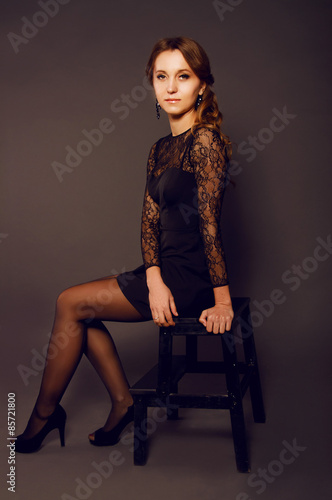 Elegant young woman in black lace dress with long curly hair