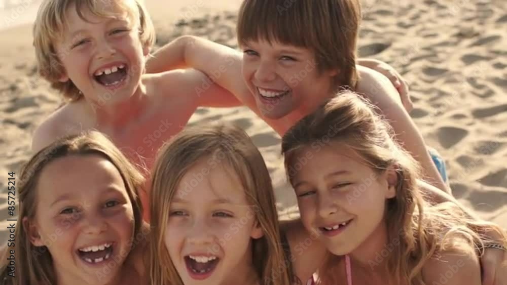 Close up of five children on beach facing camera and laughing. Close up of five children on beach facing camera and laughing.