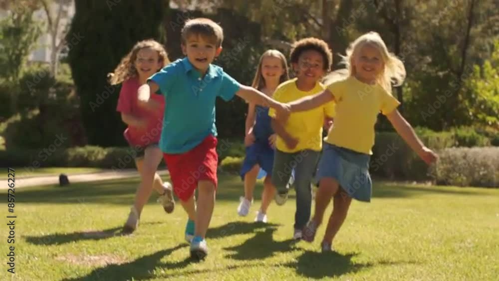 Tilt up slow motion shot of five children running towards camera in park. Tilt up slow motion shot of five children running towards camera in park.