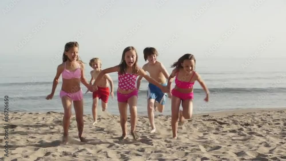 Slow motion of five children running towards camera on beach. Slow motion of five children running towards camera on beach.