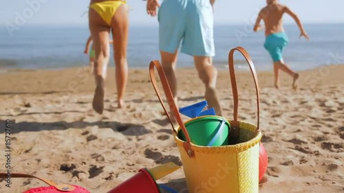 family dropping bags and running down beach to sea