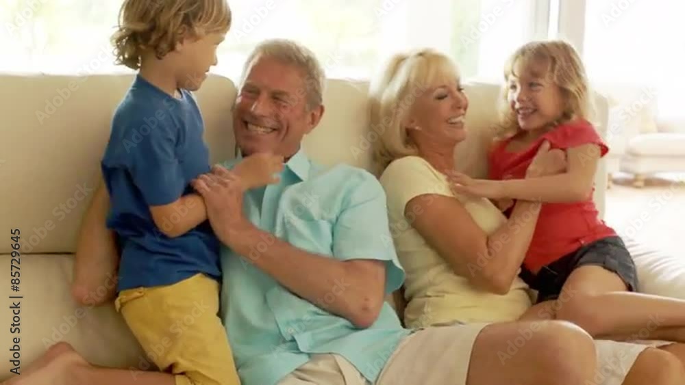 Grandchildren running to grandparents and hugging on sofa indoors. Grandchildren running to grandparents and hugging on sofa indoors.