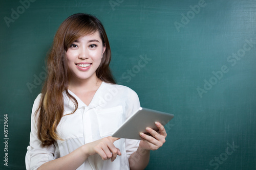 asian beautiful woman holding tablet in front of blackboard