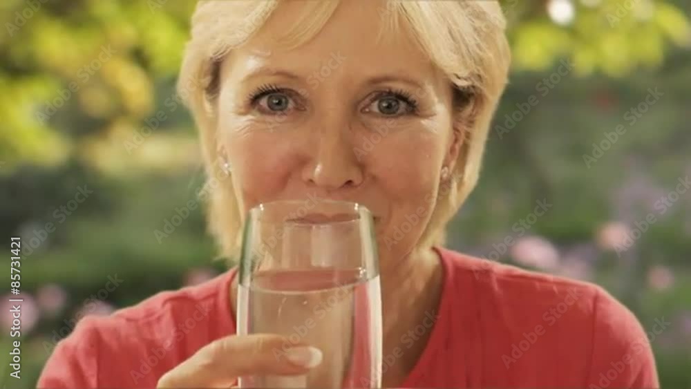 woman drinking glass of water with garden background woman drinking glass of water with garden background