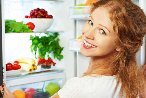 Happy woman and open refrigerator with fruits, vegetables and he