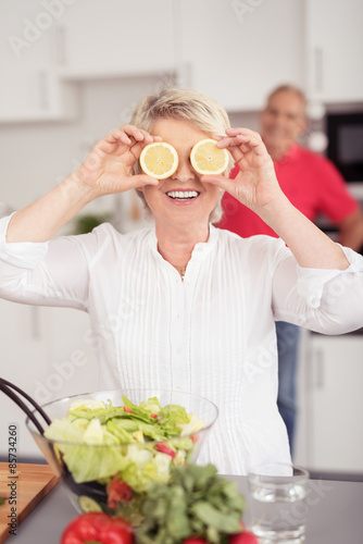 lachende seniorin hält sich zitronenscheiben vor die augen photo