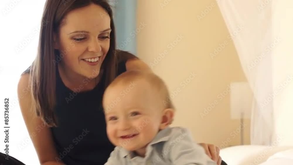 Slow motion of mother and 12 month old baby playing on bed indoors. Slow motion of mother and 12 month old baby playing on bed indoors.