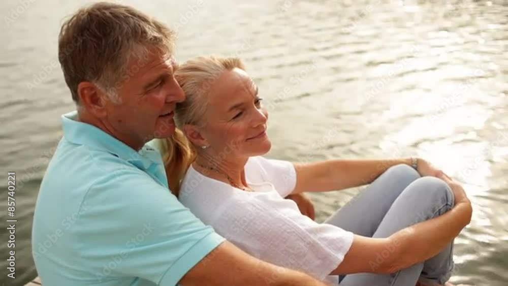 Mature couple sitting on jetty by lakeside Mature couple sitting on jetty by lakeside