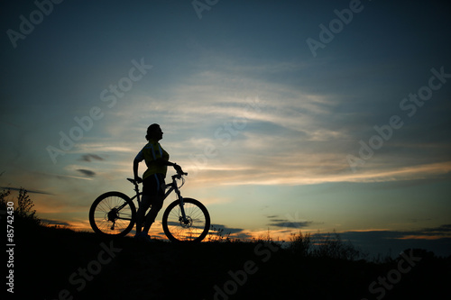 Fototapeta Naklejka Na Ścianę i Meble -  Silhouette of tourist and bike on sky background.