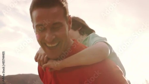 Slow motion of father with son on back playing in countryside.