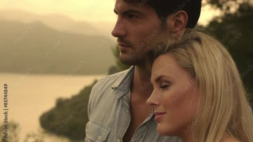 Young couple standing together by water's edge. Young couple standing together by water's edge.