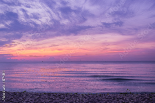 Sunrise sky over sea and beach in purple filter.