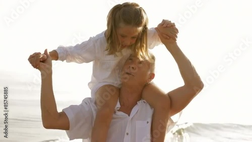 grandfather and granddaughter playing on beach 