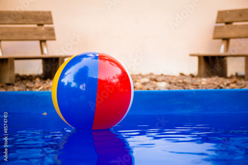 Colorful beach ball floating in pool