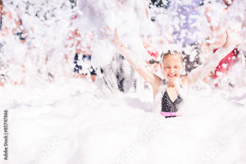 Cute little girl having fun at foam party.