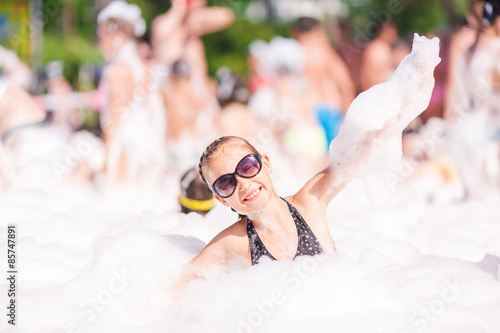 Cute little girl having fun at foam party.