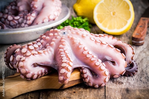 whole fresh raw octopus  on cutting board with lemon photo