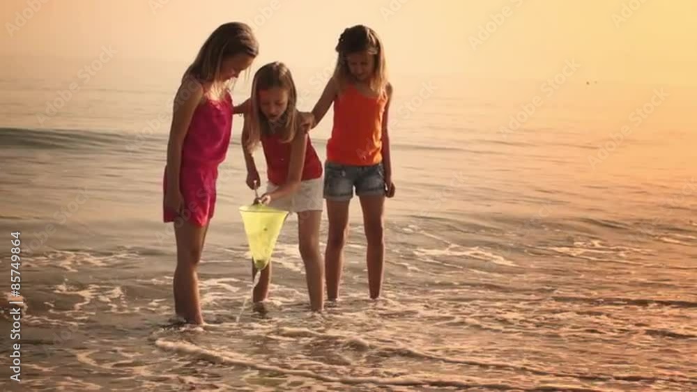 Three girls playing with fishing net in surf. Three girls playing with fishing net in surf.