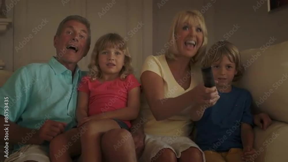 Grandparents and grandchildren in living room watching television on sofa. Grandparents and grandchildren in living room watching television on sofa.