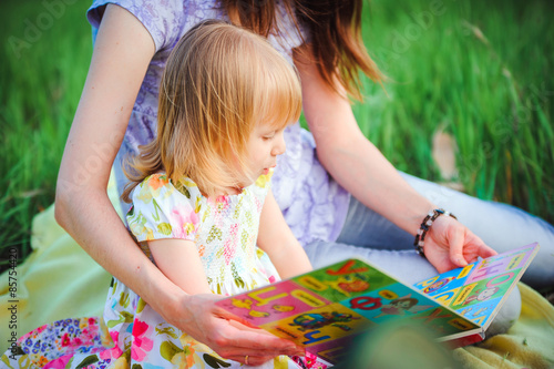 Mom and daughter reading a book in the park