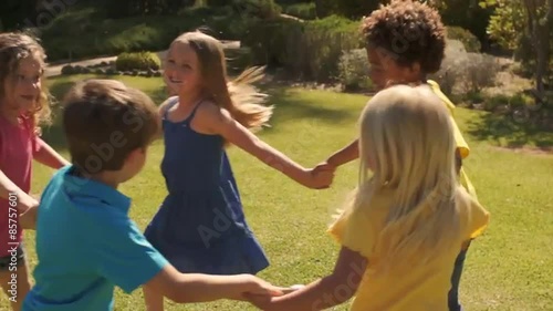 Five children paying ring-a-roses in park.