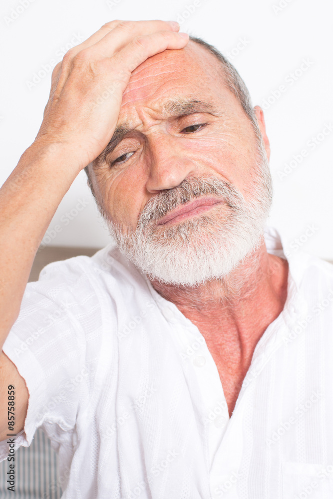 Obraz premium Elderly man sitting on bed with hangover