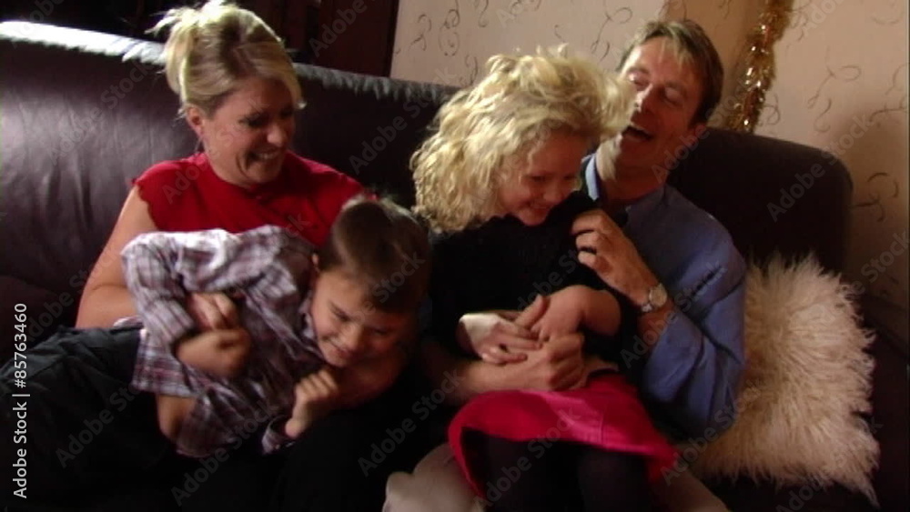 Parents cuddling children on sofa. Parents cuddling children on sofa.