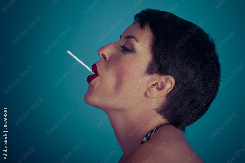 Obraz premium Sweet, happy young woman with lollypop in her mouth on blue