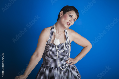 Sweet, happy young woman with lollypop in her mouth on blue