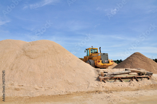 Photos Bulldozer entre des tas de sable sous un beau ciel bleu