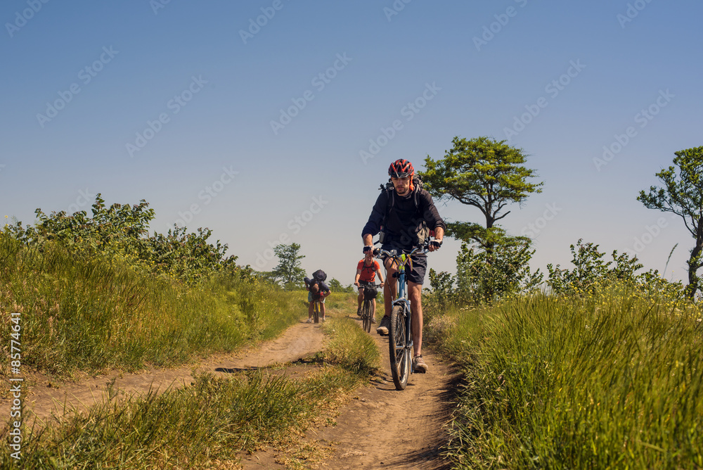 young caucasian cyclists riding in the field