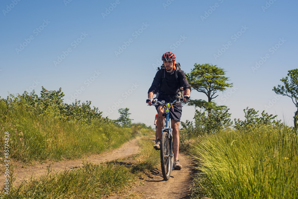 Naklejka premium young caucasian cyclists riding in the field