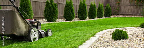 Obraz na płótnie Lawn mower cutting green grass in backyard, mowing lawn