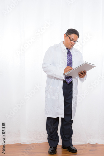 Latino Male Wearing Lab Coat And Holding Clipboard