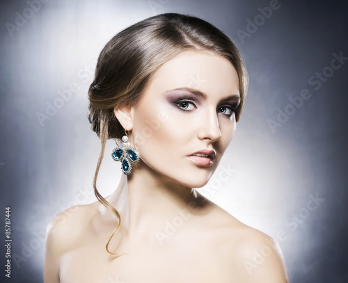 Young  beautiful and rich woman in jewels. Metal background