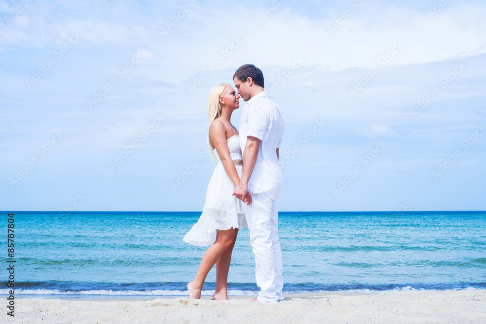 Loving couple walking and embracing on a tropical summer beach