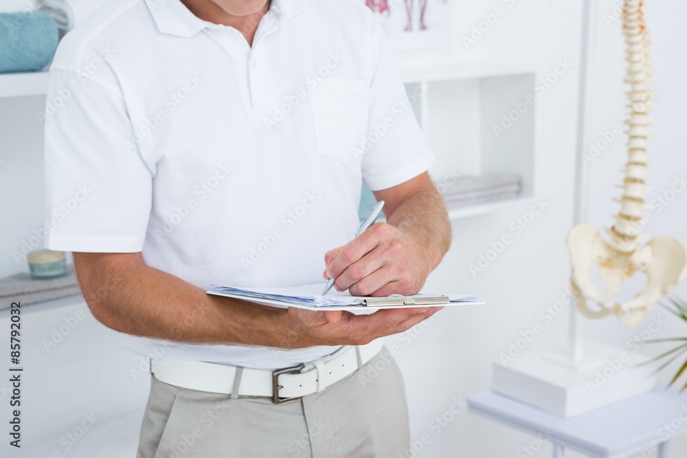 Doctor writing on clipboard