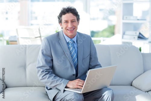Smiling businessman using his laptop on couch © WavebreakMediaMicro