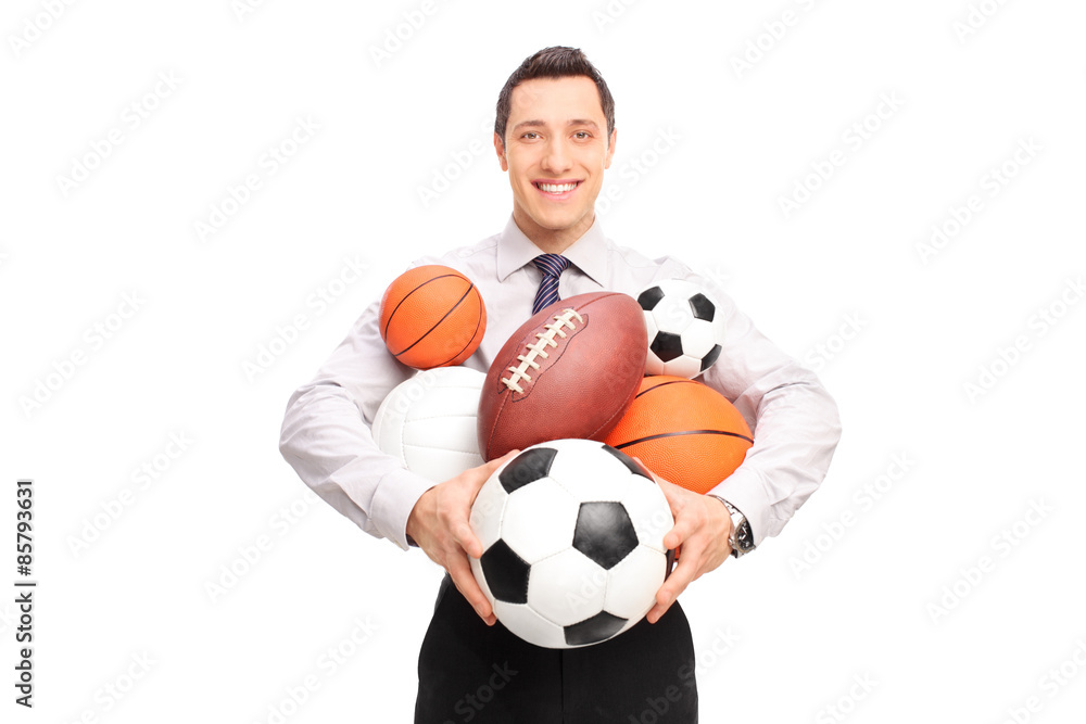 Man holding a bunch of different kind of sports balls