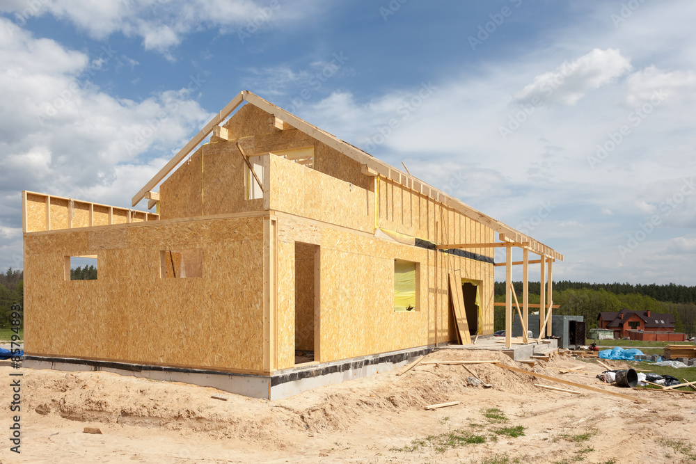 New residential frame house under construction against a blue sky New residential frame house under construction against a blue sky