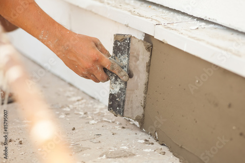 Man hand with trowel plastering a foundation of house