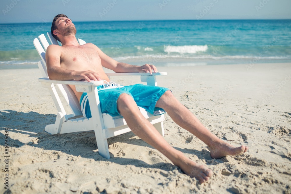 Man relaxing on deck chair at the beach Man relaxing on deck chair at the beach