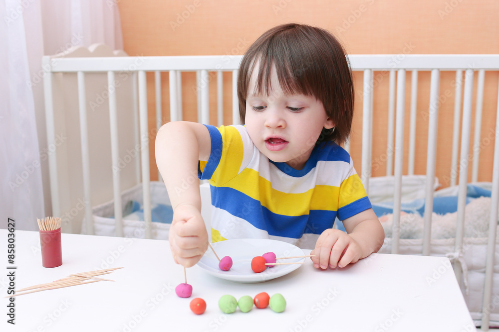 Cute little child made lollipops of playdough and toothpicks Cute little child made lollipops of playdough and toothpicks